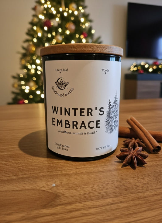 Winter’s Embrace luxury Christmas candle styled with cinnamon beside a decorated Christmas tree